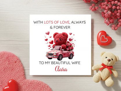 Valentine's Day card with teddy bear and car illustration, surrounded by decorative elements on a wooden surface.